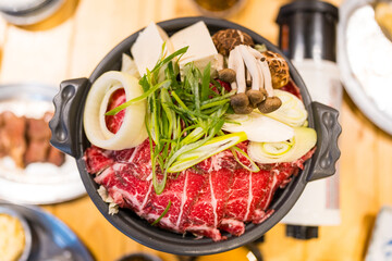 Delicious hotpot with fresh beef and various vegetable cooking in a hot pot. Top view