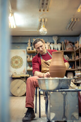 A man is making pottery on a potter's wheel. A man makes pottery. Clay modeling.