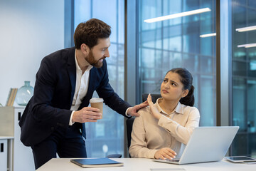 A woman at work rebuffs unwanted attention from a male colleague, conveying discomfort and...