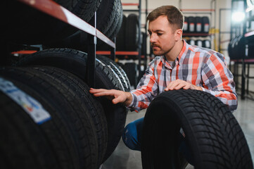 Portrait young man customer examining brand and product characteristics while buying new tires in...