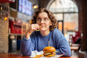 Young woman eating burger. Fast food. Cheat Meal. A woman in a burger restaurant.