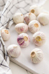 Solo glove garlic bulbs on white table.