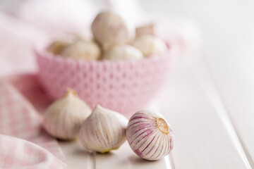 Solo glove garlic bulbs on white table.