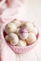 Solo glove garlic bulbs in bowl on white table.