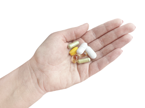 Human hand holding a handful of dietary supplement pills, isolated on transparent background. Variety of bioactive capsules and tablets for health and wellness.