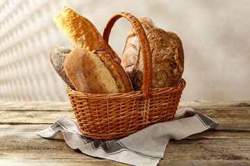 Different loaves of fresh bread in basket on wooden table, closeup