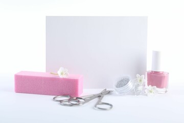 Set of different manicure tools, blank card and flowers on white background, closeup