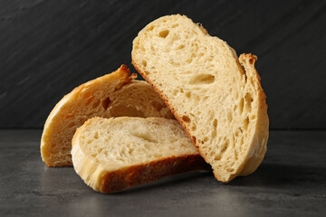 Slices of fresh bread on dark textured table against black background, closeup