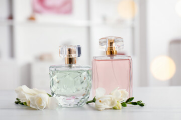 Bottles of perfume and beautiful flowers on white table