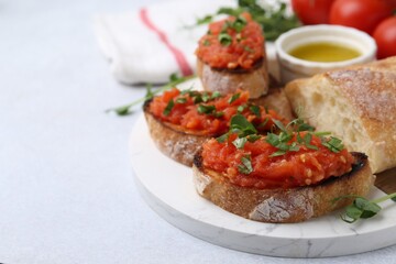Tasty bread with tomato, parsley and oil on light table, closeup. Space for text