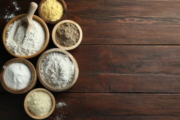 Different types of flour in bowls on wooden table, flat lay. Space for text