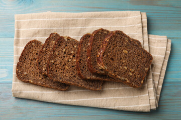 Pieces of fresh bread on light blue wooden table, top view