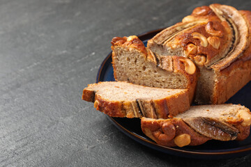 Cut banana bread with nuts on black table, closeup. Space for text