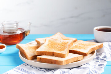 Slices of tasty toasted bread on light blue wooden table against grey background, closeup