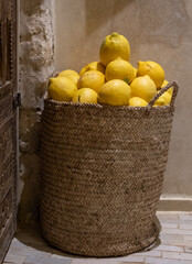Ripe lemons piled high in a rattan wicker basket, photographed in Marrakech, Morocco.