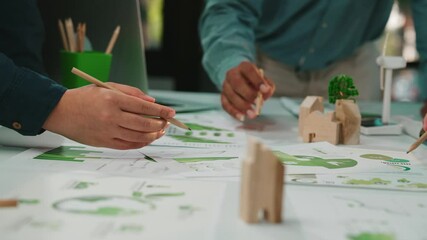 A diverse group collaborates in a workspace, analyzing charts and models related to sustainable development, showcasing teamwork and innovative strategies for growth. SACTR