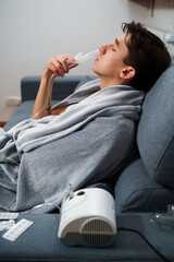 Young man with asthma attack breathing with inhaler in the bad. Doing nose inhalation with...