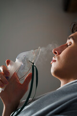 Using compressor nebulizer for disease treatment at home. Man inhaling through oxygen mask for...