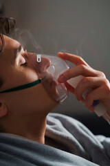 Using compressor nebulizer for disease treatment at home. Man inhaling through oxygen mask for...