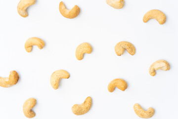 Scattered roasted cashew nuts on a clean white background, ideal for minimalist food designs,...