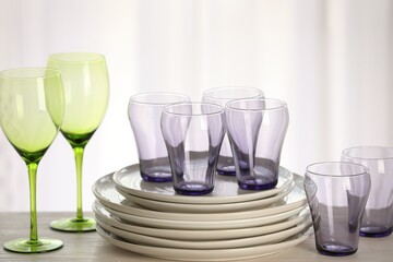 Empty clean glasses and plates on wooden table indoors