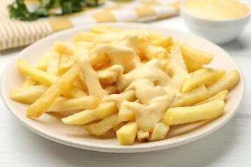 French fries with cheese sauce on white wooden table, closeup