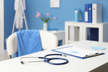 Doctor's workplace. Clipboard, other stationery and stethoscope on white table in medical office, closeup