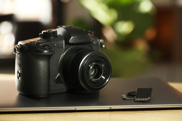 SD memory cards, laptop and photo camera on wooden table, closeup