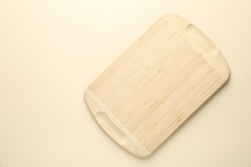 One wooden cutting board on beige table, top view. Space for text
