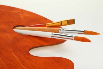 Wooden palette and brushes on white background, closeup
