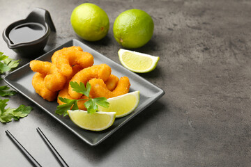 Tasty tempura shrimps, lime, parsley and soy sauce on grey textured table, closeup. Space for text