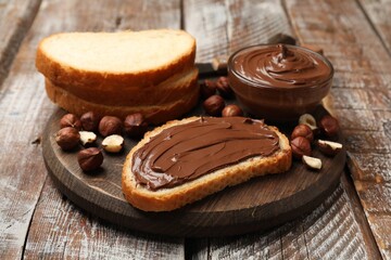 Toast with chocolate hazelnut spread and nuts on wooden table, closeup