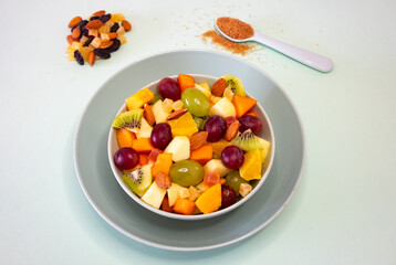 Close up on a green bowl full of fresh and colorful fruit. Apple, kiwi, orange, papaya, grape, mango, melon. Breakfast or break, healthy eating