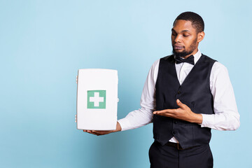 Hotel porter personnel presenting a first aid kit used for medical emergencies, advertising...
