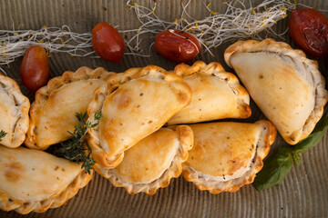 Hot finger food with a rustic presentation. Top view of gourmet traditional crispy meat empanadas with criolla sauce in a textured dish