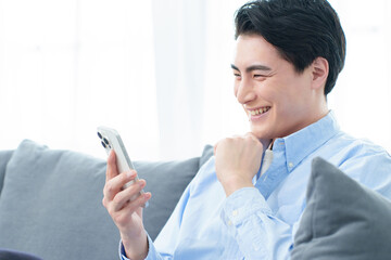 リビングでスマートフォンを使う男性