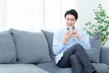 リビングでスマートフォンを使う男性