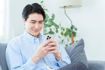 リビングでスマートフォンを使う男性