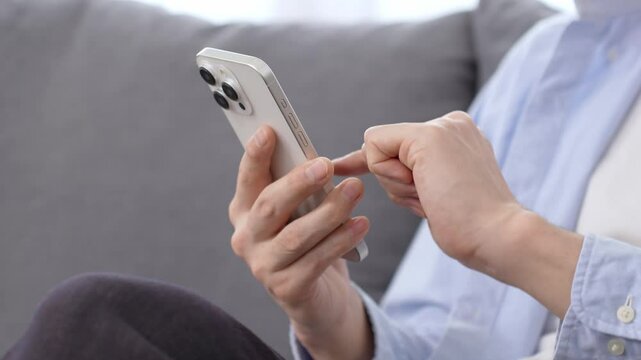 リビングでスマートフォンを使う男性の手元