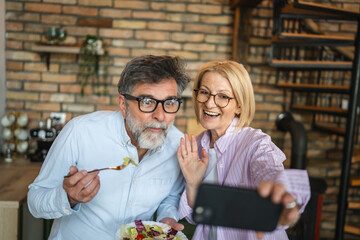 mature happy couple take a self portrait on cellphone with salad