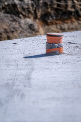 A small plastic fitting protruding from the concrete with a cap.
