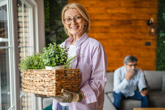 Portrait of beautiful mature woman hold basket with potted plants