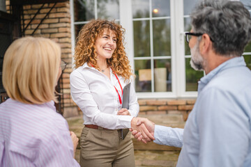 customers shake hands with real estate agent agree to sign a contract