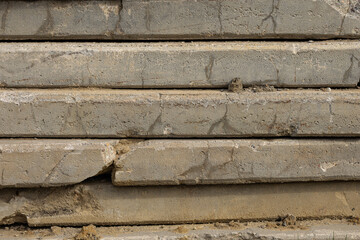 Stack of rough cracked concrete slabs with visible texture, dirt and signs of wear at construction site on sunny day. Materials of building, industrial work, urban development and durability