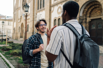 Two cheerful male students chatting and walking near university building