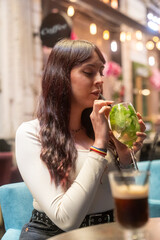 Young woman enjoying refreshing cocktail in outdoor cafe
