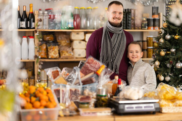 Young male buyer with his son while shopping in grocery store decorated for christmas