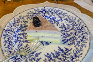 Slice of Chantilly Cake with blackberries and blueberries over a light blackberry frosting