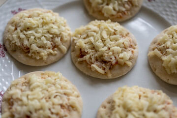 Small mini pizza with cheese on a white plate.
