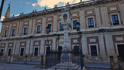 Archive of the Indies of Seville with statue and cloudy sky in the background